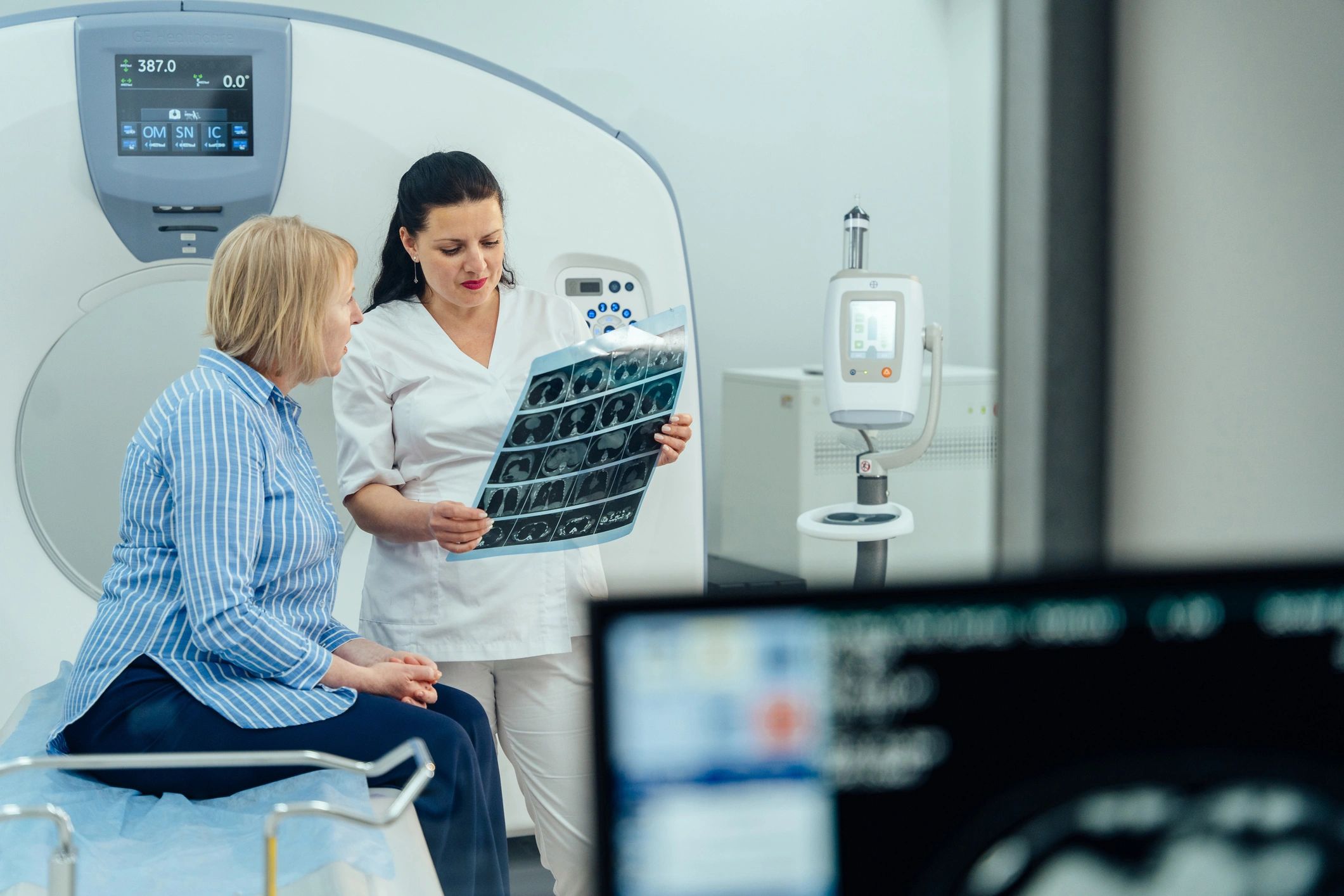 A woman is sitting in our office with a technician looking at a medical image.