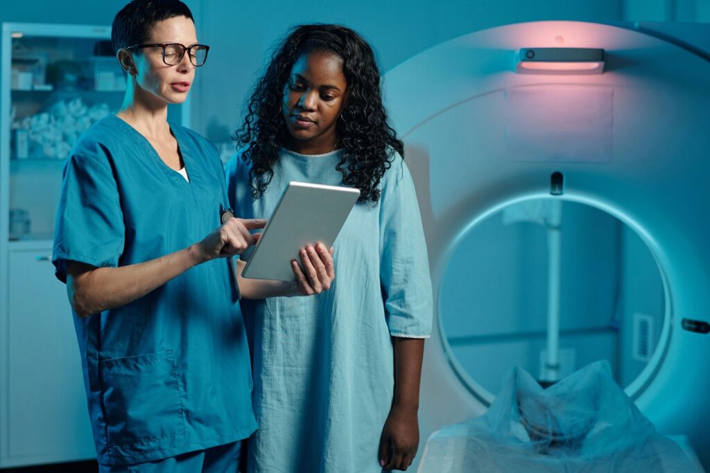 A medical professional is examining Patient Instructions with tablet in imaging room. Background features our advanced medical equipment and scanning device, highlighting healthcare technology.